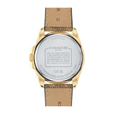 The back view of a Coach watch with a gold-toned case and a light brown leather strap, showing the detailed specifications printed on the back of the case.
