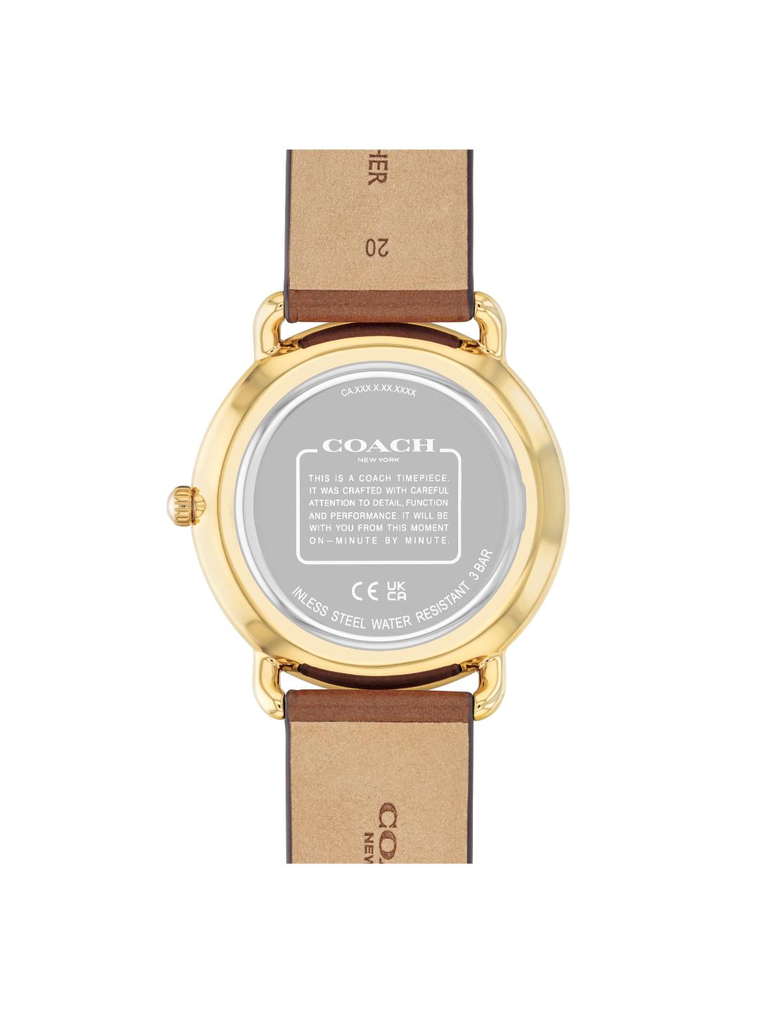 The back view of a Coach wristwatch with a gold-tone case and a brown leather strap, showing the brand name and technical specifications on the crystal.