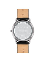The back view of a Coach wristwatch with a round silver-tone stainless steel case and a light tan leather strap, shown on a plain white background.