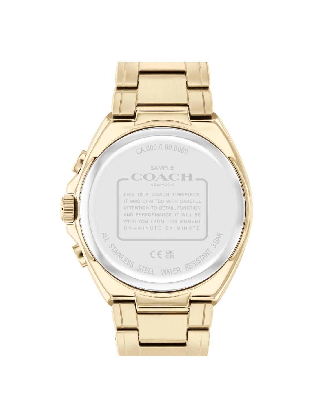 The back view of a Coach stainless steel watch with a gold-tone case and integrated link bracelet, showing engraved specifications on the crystal.