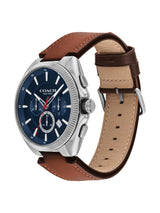 A Coach New York men's watch featuring a silver-tone stainless steel case, a dark blue dial with chronograph subdials, and a brown leather strap with a tan interior, shown on a plain white background.