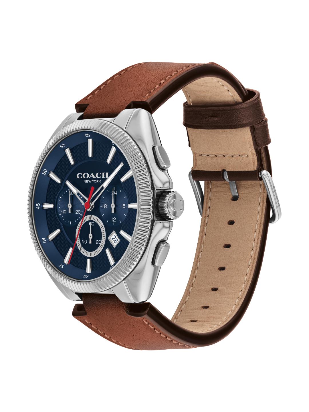 A Coach New York men's watch featuring a silver-tone stainless steel case, a dark blue dial with chronograph subdials, and a brown leather strap with a tan interior, shown on a plain white background.