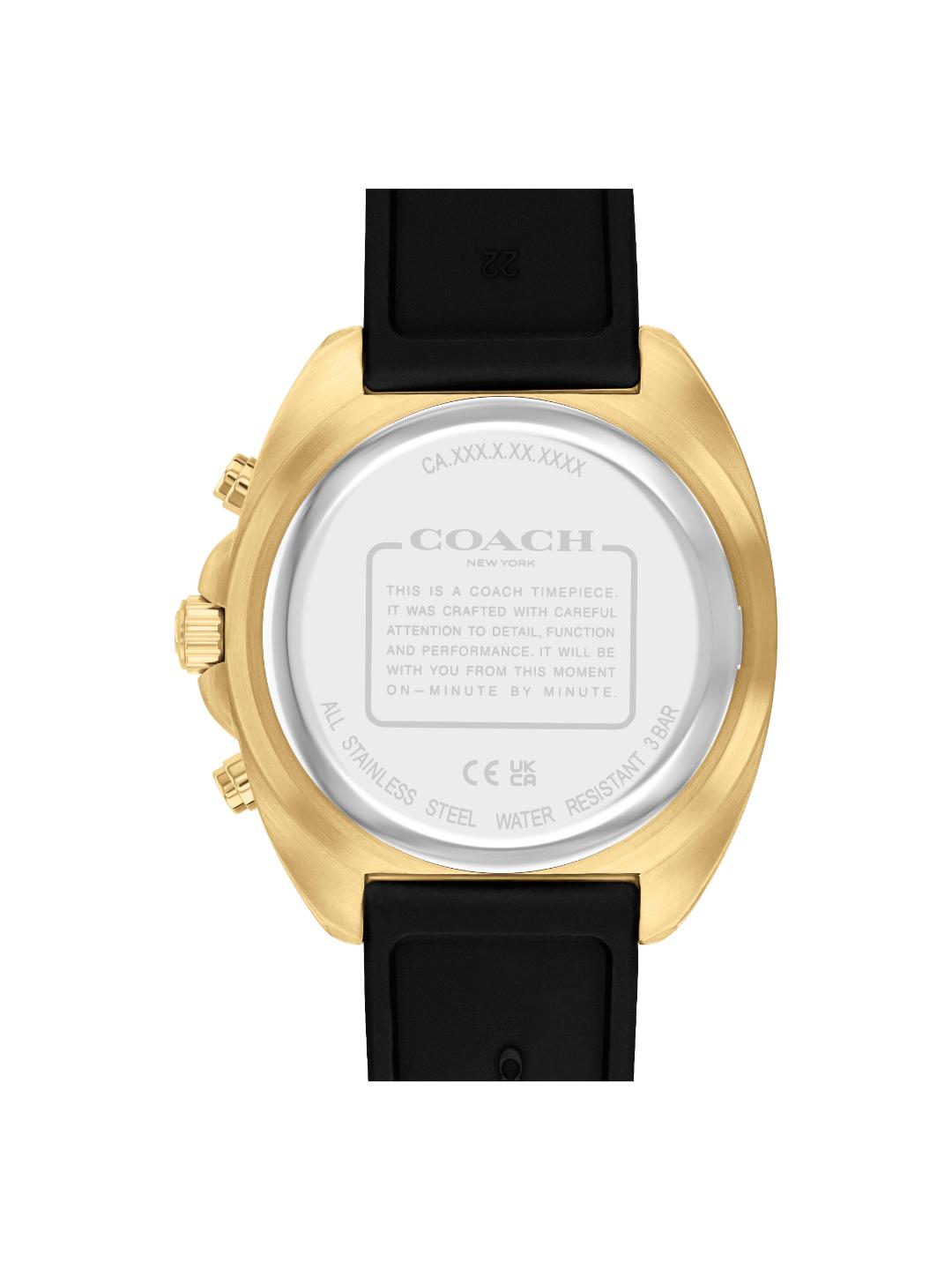 The back view of a Coach wristwatch with a gold-tone case and a black strap, showing the brushed silver-toned case back with engraved details.