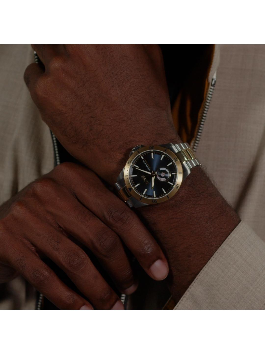 A close-up of a man's wrist wearing a two-tone metal watch with a gold bezel, silver bracelet, and a dark blue dial.