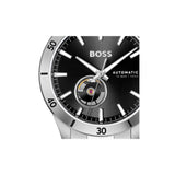 Close-up of a Hugo Boss automatic watch with a black dial, silver-tone case, and black bezel, featuring a visible tourbillon movement at the 6 o'clock position.