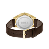 The back view of a HUGO BOSS watch with a dark brown leather strap and a gold-tone case, showing the brushed silver-tone case back engraved with the BOSS logo.