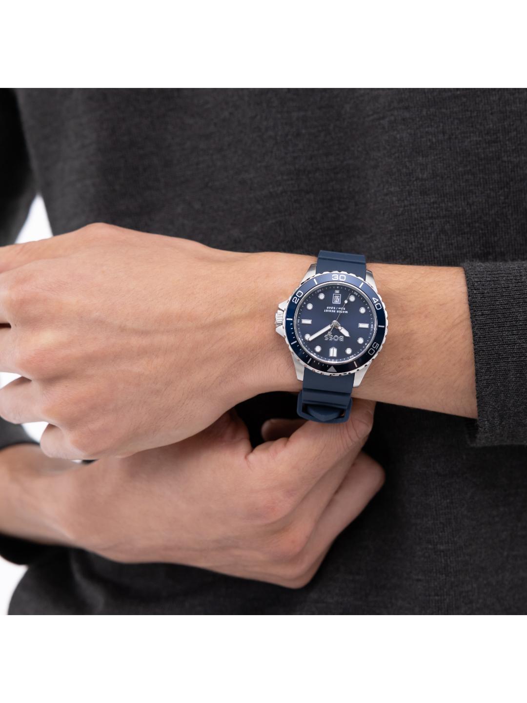 A close-up of a person's wrist wearing a Seiko Oyster Perpetual watch with a dark blue silicone strap, silver-tone case, and blue dial.