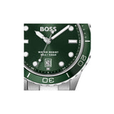 A close-up of a BOSS watch with a dark green dial and bezel, silver-tone stainless steel case and bracelet, and white hour markers.