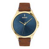 Hugo watch with a round gold-tone case, a textured blue dial, and a brown leather strap with visible blue stitching.