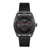 A Hugo brand men's watch featuring a black leather strap, a dark gray metal case, and a black dial with red accents and white sub-dials.