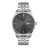 A silver-tone stainless steel watch with a textured dark gray dial, silver-tone hour markers and hands, and a distinctive green second hand. The watch features the Lacoste crocodile logo on the dial and is shown against a plain white background.