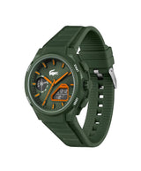 A Lacoste sport watch with an olive green silicone strap, matching green textured dial, and bright orange accents on the hands, markers, and digital display.