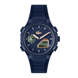 A Lacoste digital watch with a dark navy blue case and textured strap, featuring a textured blue dial with gold-tone hands, a green day-of-week indicator, and a digital LCD display.
