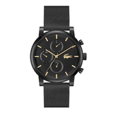 A black chronograph watch with a black mesh strap, featuring gold-tone hands, indices, and the Lacoste crocodile logo on the dial, set against a plain white background.