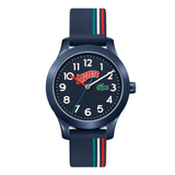 A Lacoste kids' analog watch with a dark blue case, a black dial featuring white Arabic numerals and a red Lacoste logo, and a navy blue strap with red, white, and green stripes.