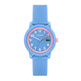A Lacoste kids' watch with a light blue silicone strap and case, featuring a blue dial with a pink inner ring, white Arabic numerals, and a green crocodile logo.