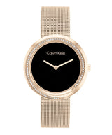 Calvin Klein watch with rose gold mesh band and black dial on a white background