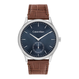 Calvin Klein men's watch featuring a dark blue dial, silver-tone stainless steel case, and a brown leather strap with an alligator pattern.