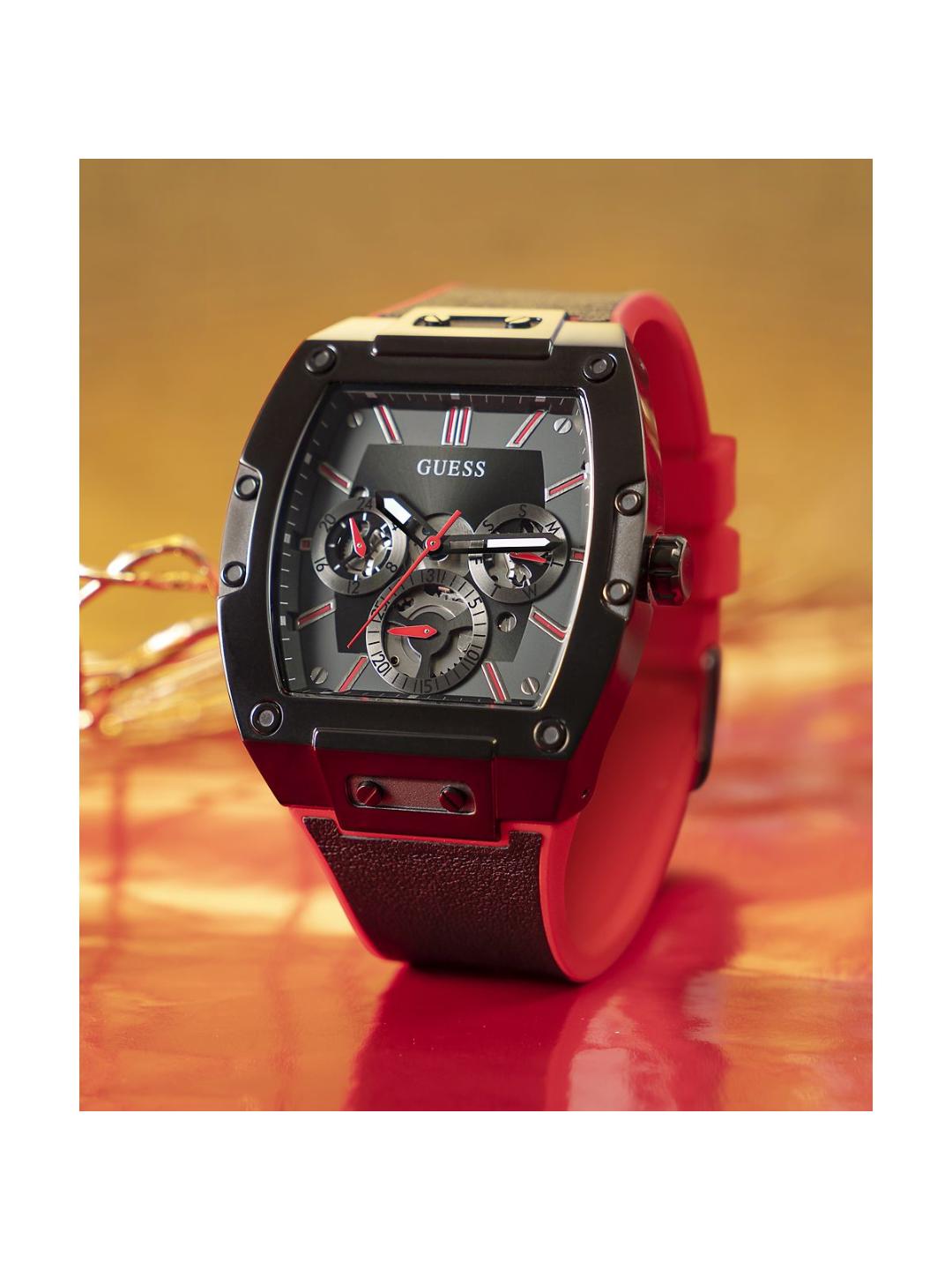 Red and black Guess watch on a wooden surface with a blurred background