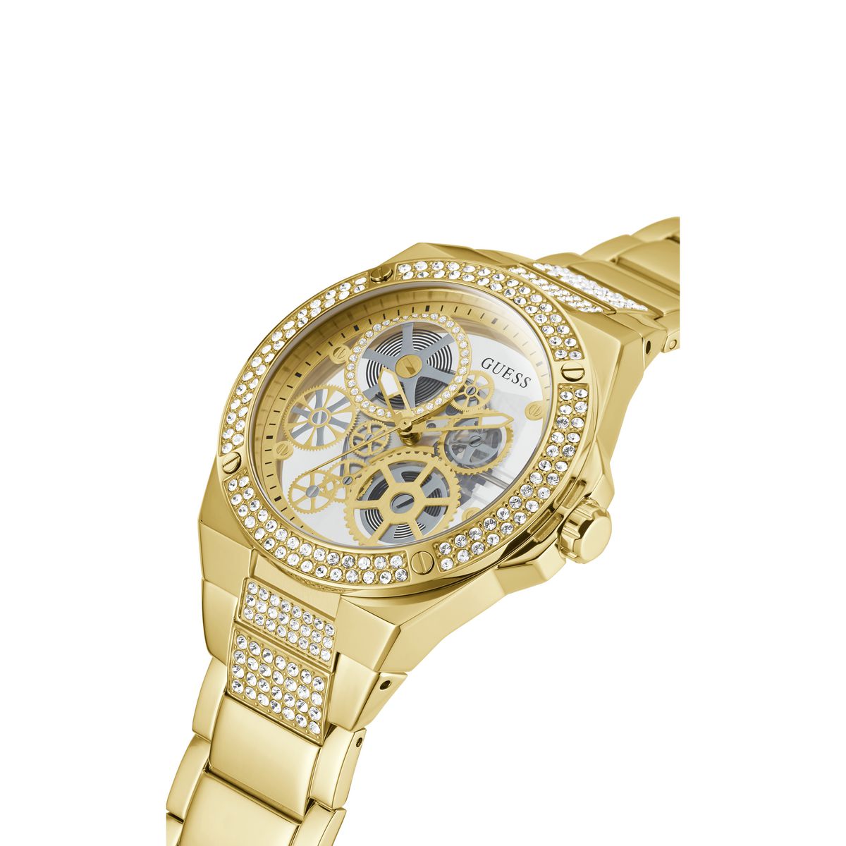 Gold-tone Guess women's watch with a crystal-studded bezel, skeletonized white dial showing gold gears, and a crystal-accented metal link bracelet on a white background.