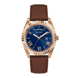 A GUESS men's analog watch featuring a rose gold-tone case with a fluted bezel, a deep blue dial with gold-tone Roman numerals and hands, and a brown leather strap.