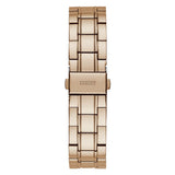 A rose gold metal link watch band shown vertically against a plain white background, featuring the 'GUESS' brand logo engraved on the clasp.