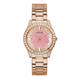 A Guess women's analog watch with a rose gold metal link bracelet, a crystal-studded bezel, and a pink glitter dial.