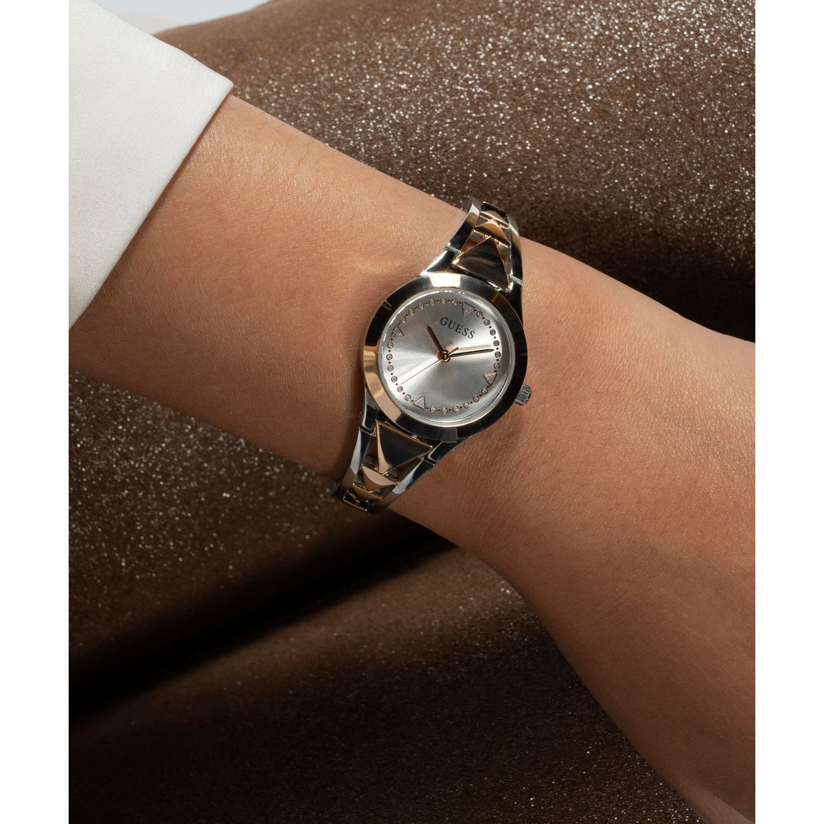 Silver watch on a wrist with a brown textured background