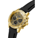 A gold-tone Guess chronograph watch with a black textured dial, black sub-dials, a bezel set with clear crystals, and a black rubber strap, shown on a white background.