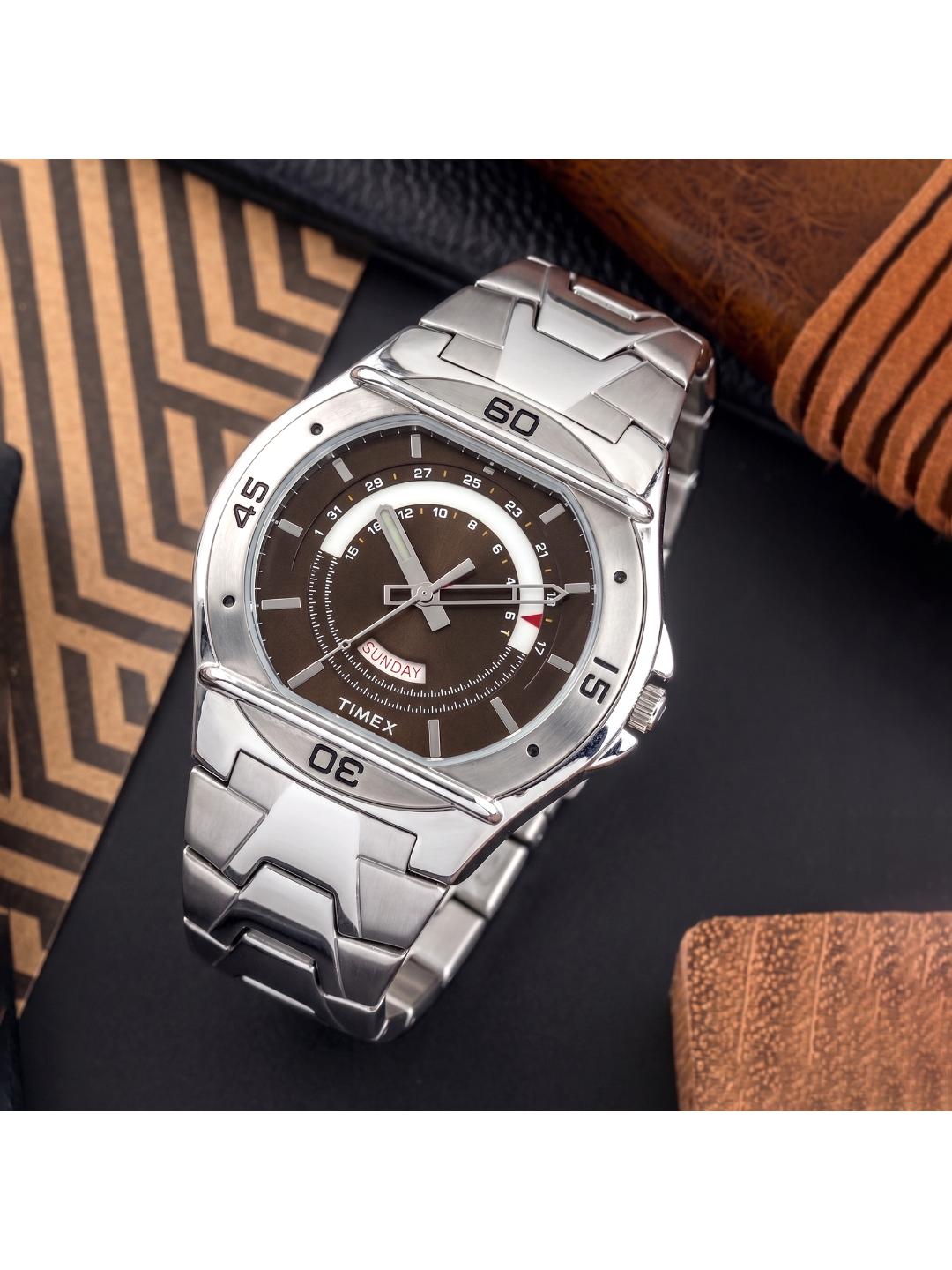 Silver Timex watch with a brown face on a dark surface with a textured brown background