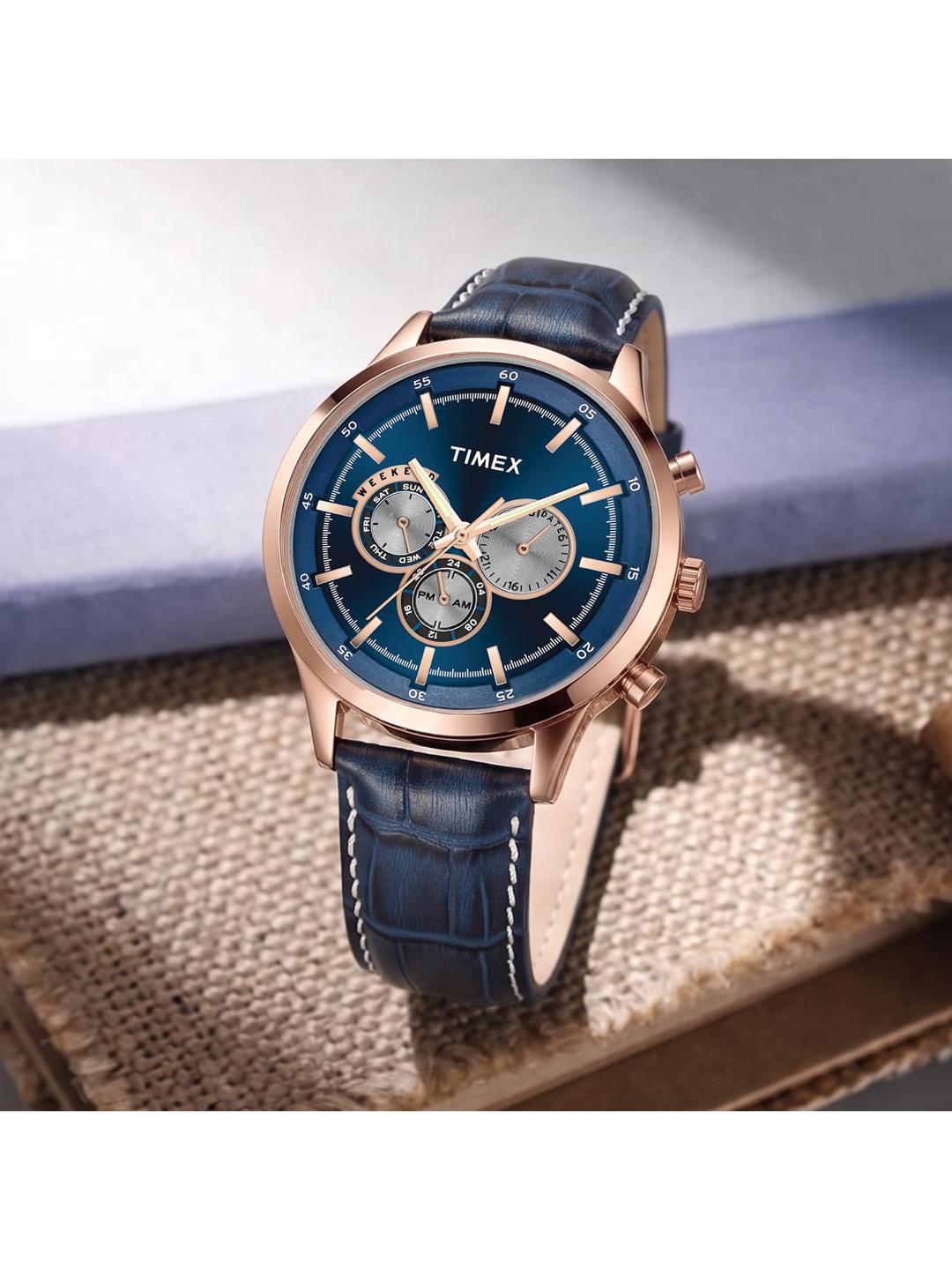 Timex watch with blue face and leather strap on a textured surface