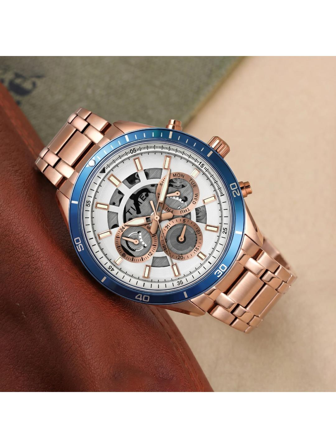 Rose gold and blue watch on a wrist with a neutral background