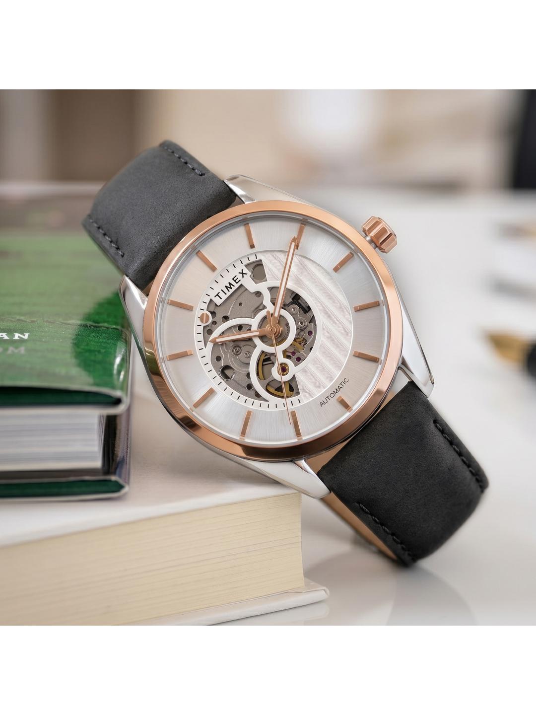 Watch with black leather strap and rose gold case on a white surface