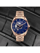 Rose gold Timex watch with a blue face on a black textured background