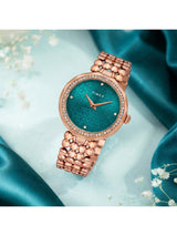 Timex watch with rose gold band and teal face on a blue fabric background