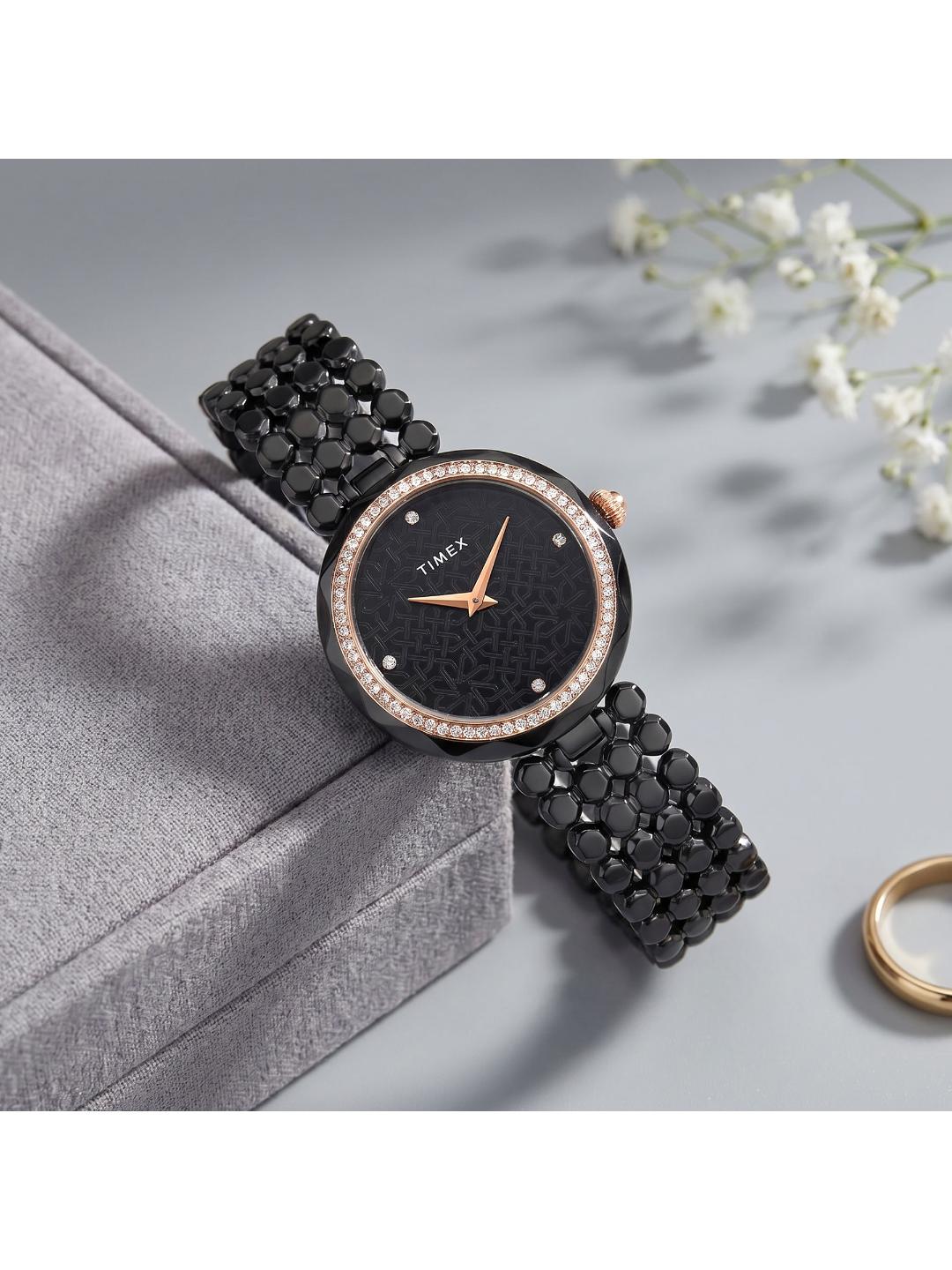 Black watch with rose gold accents on a gray surface with white flowers in the background