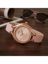 Pink Timex watch with rose gold accents on a wooden surface