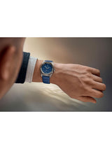 Person wearing a blue watch on a neutral background